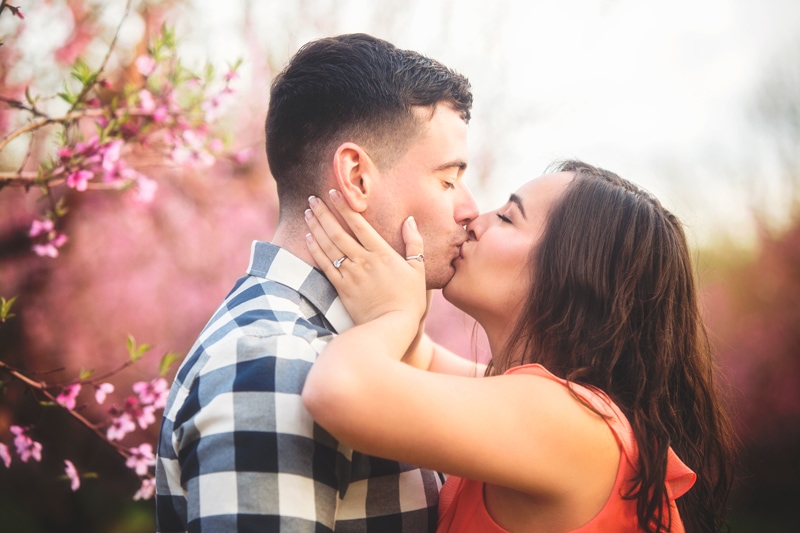 Couples Photographer, woman holding man's cheeks and giving him a kiss
