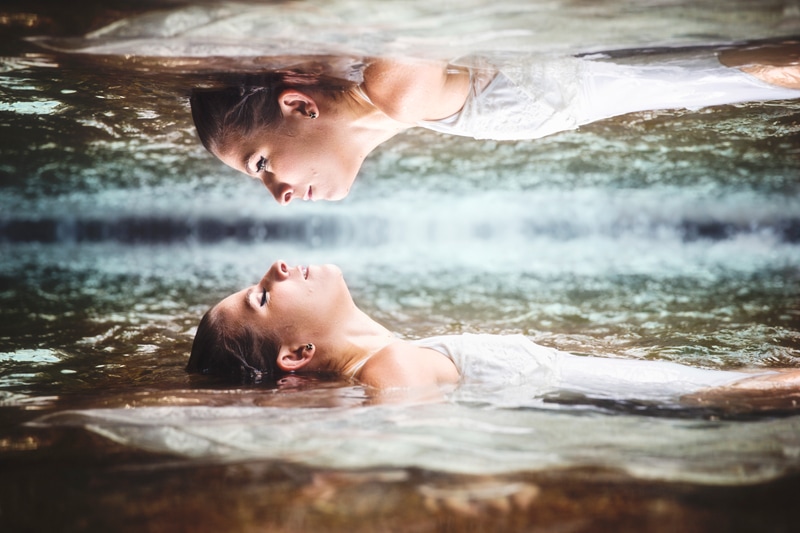 Portrait Photographer, reflection of woman floating on her back in water