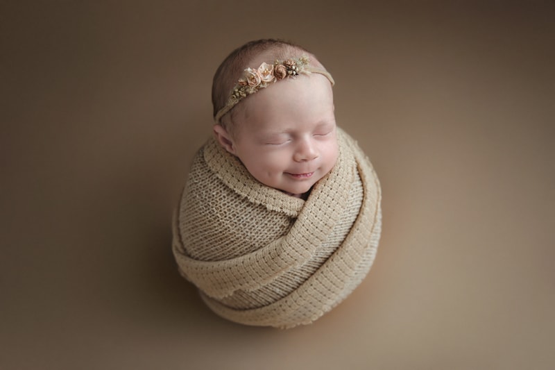 Newborn Photography, baby wrapped in brown blanket on brown background