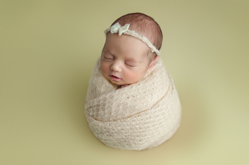 newborn photography, baby girl wrapped up on yellow background